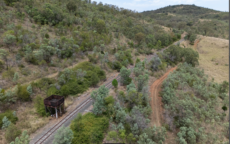 Aerial view of a railway track with surrounding trees and hills.